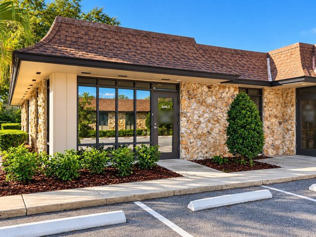 The building at 785 W Granada Blvd, Suite 3, Ormond Beach: a one-story stone front with a glass entrance to Suite 3