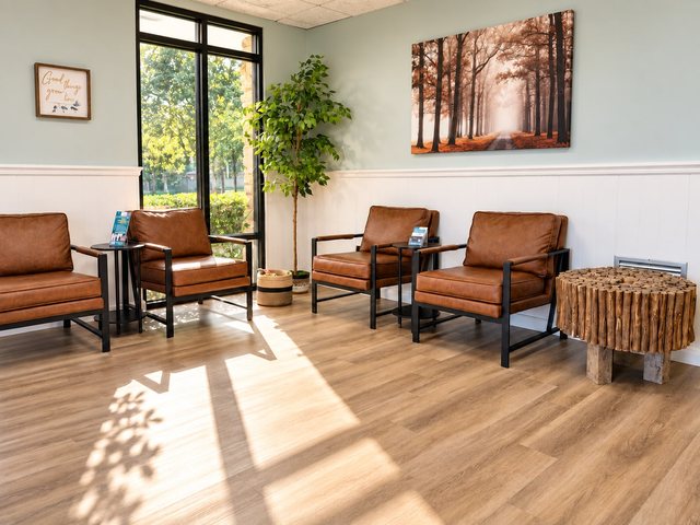 The waiting room: leather armchairs, a tall plant and a forest painting on a pale blue wall